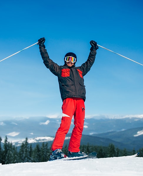 Jovem com equipamento de esqui a desfrutar da neve com vista para a montanha