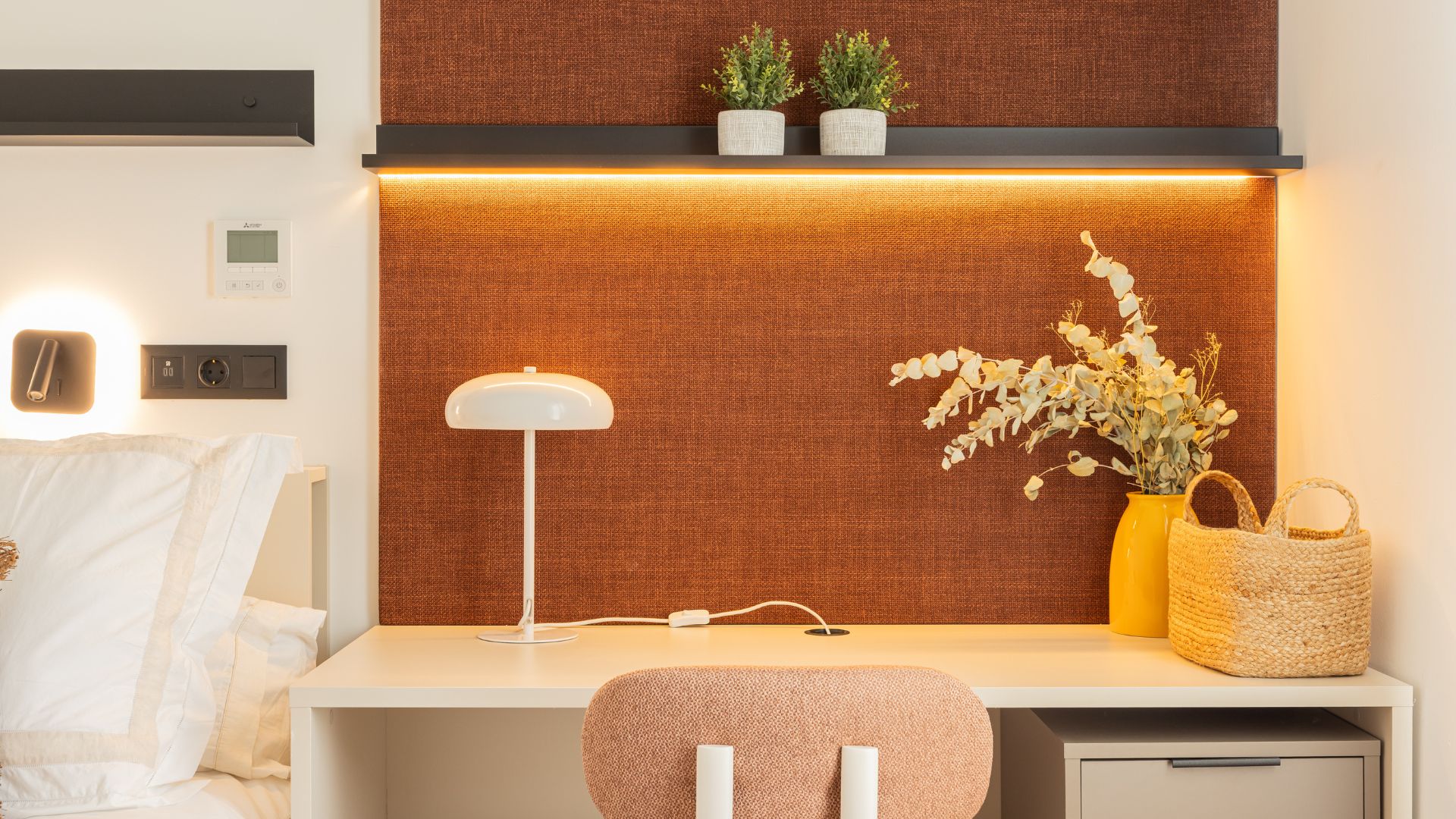 Zona de escritorio del estudio con iluminación integrada, estanterías y detalles decorativos en estilo contemporáneo.