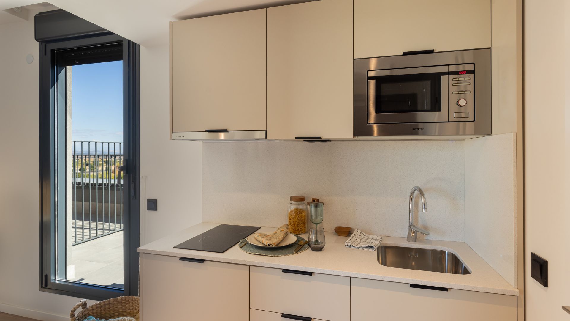 Cocina equipada del estudio con placa de inducción, microondas, fregadero y acceso directo a la terraza.