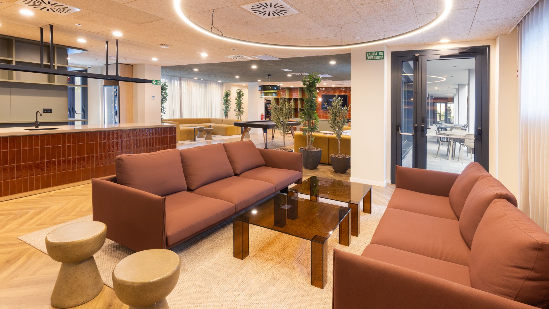 Zona común interior de la residencia universitaria de Cantoblanco, con sofás, mesas bajas y espacio social amplio.
