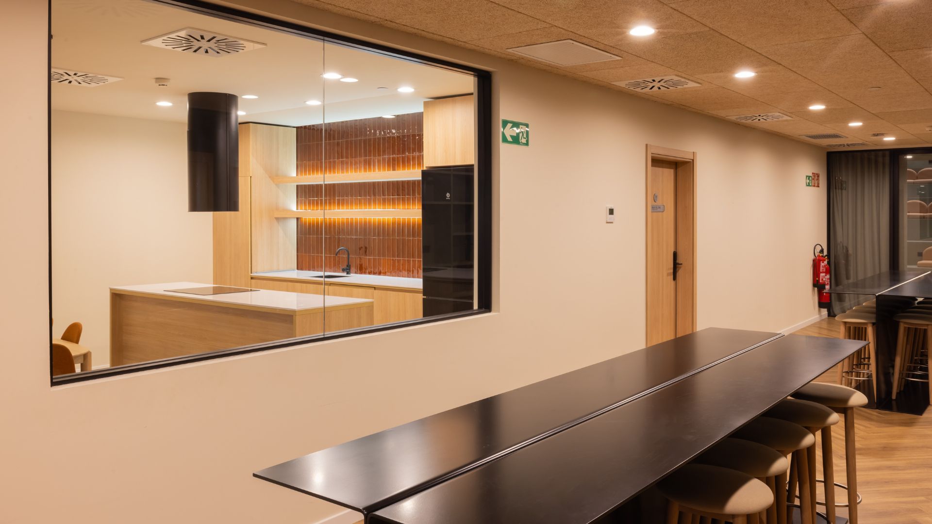 Zona de barra y mesas altas junto a cocina común en la residencia universitaria de Cantoblanco.