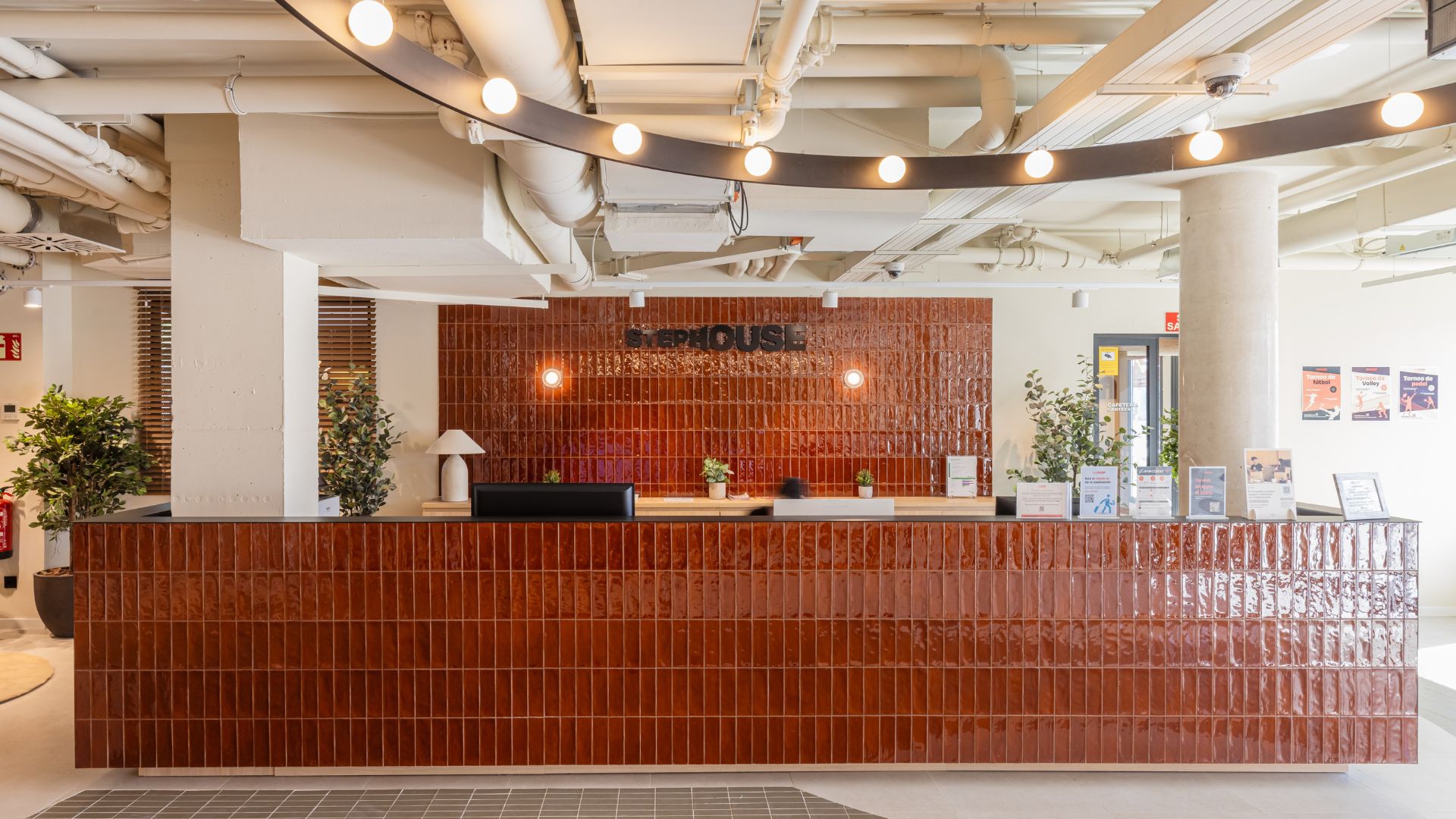 Recepción de la residencia universitaria en Cantoblanco, con mostrador, iluminación cálida y diseño contemporáneo.