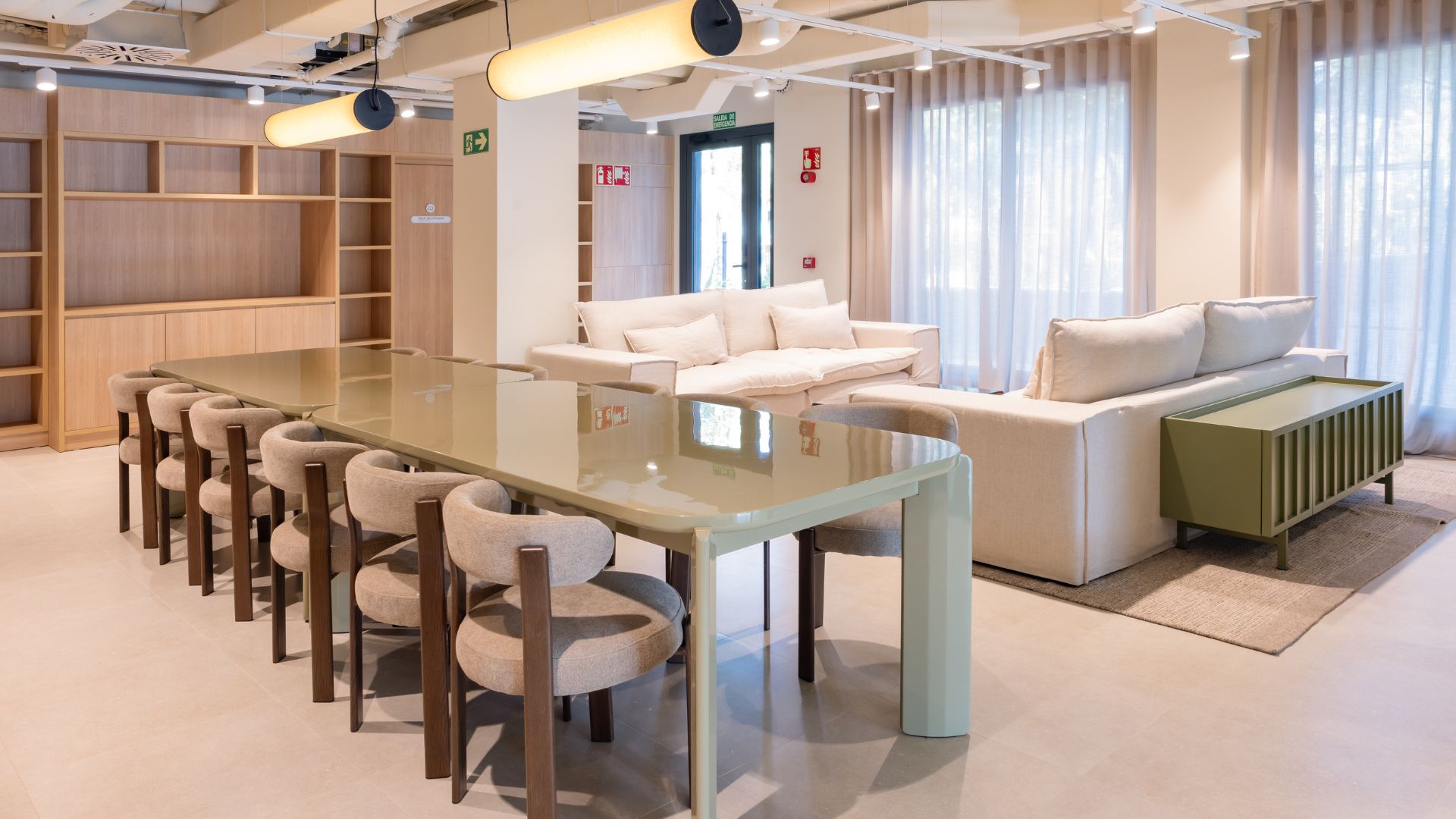 Sala de estar común en la residencia universitaria de Cantoblanco, con mesas grandes, sofás y luz natural.