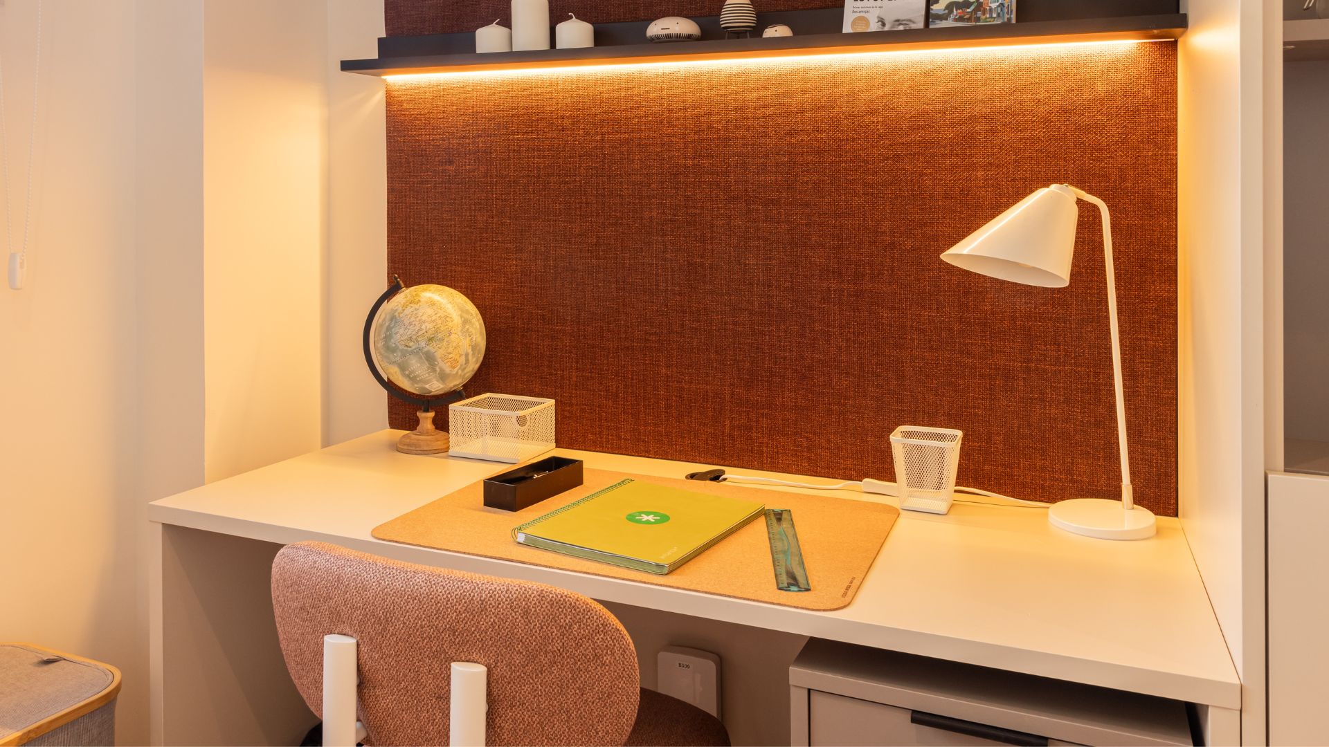 Zona de trabajo del estudio con escritorio amplio, estanterías decorativas y espacio de almacenamiento integrado.