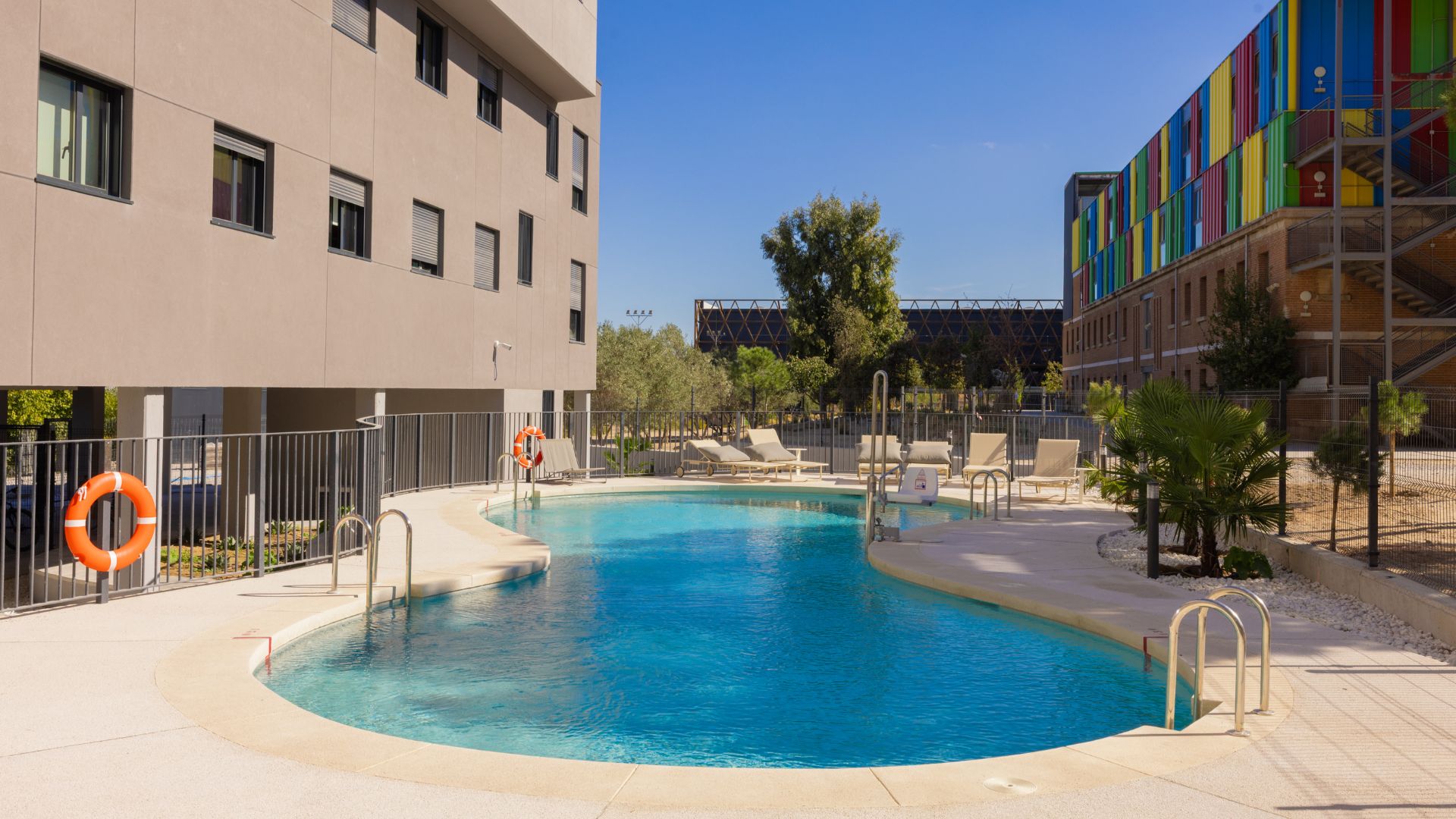 Piscina exterior en residencia universitaria de Cantoblanco, con sol, zona de descanso y ambiente tranquilo.