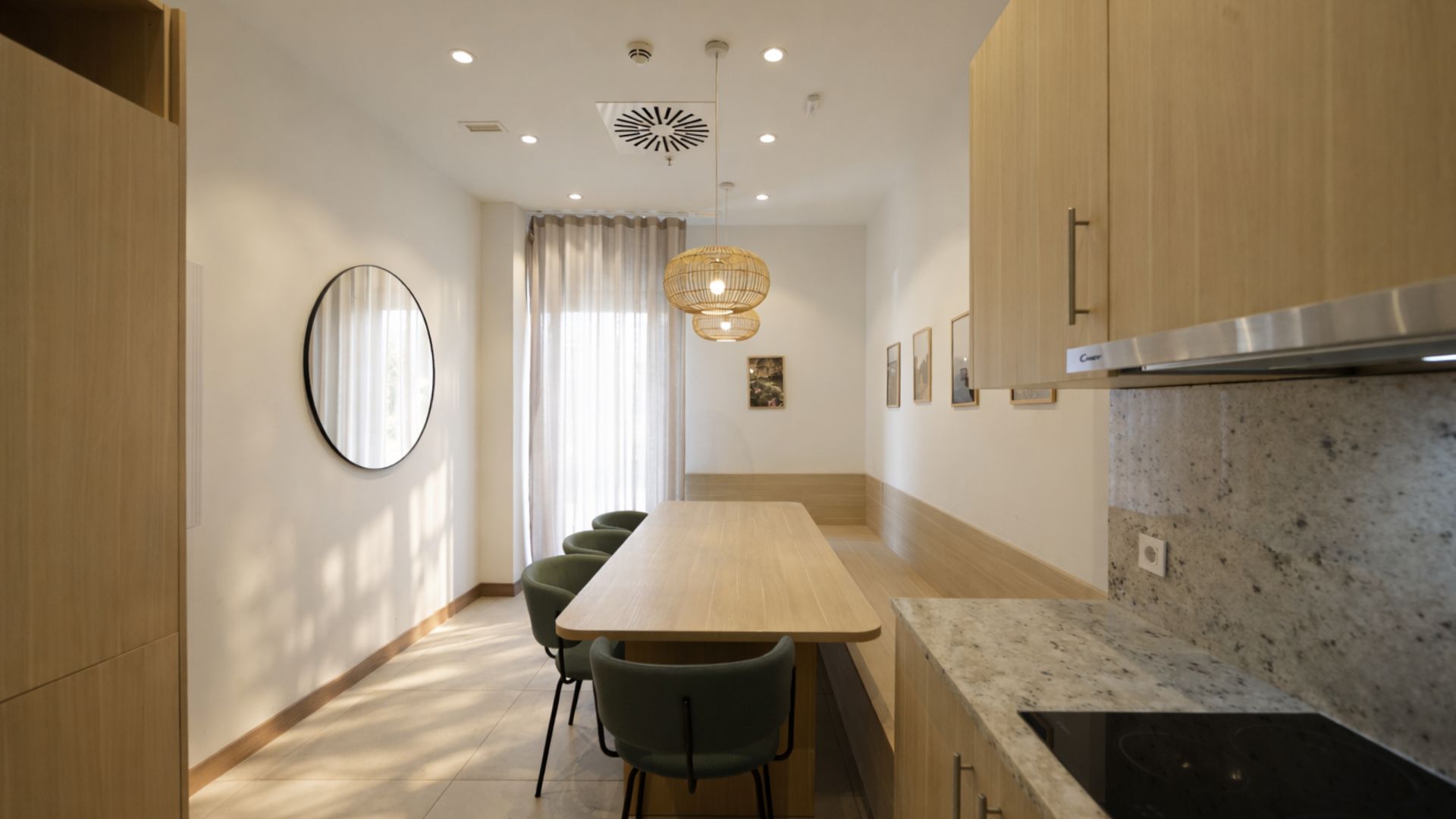 Cocina moderna y luminosa en residencia de estudiantes en Málaga con mobiliario de madera y zona office.