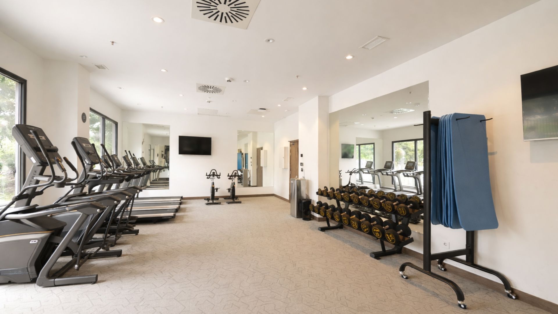 Gimnasio completamente equipado en residencia de estudiantes en Málaga con máquinas de cardio y musculación.