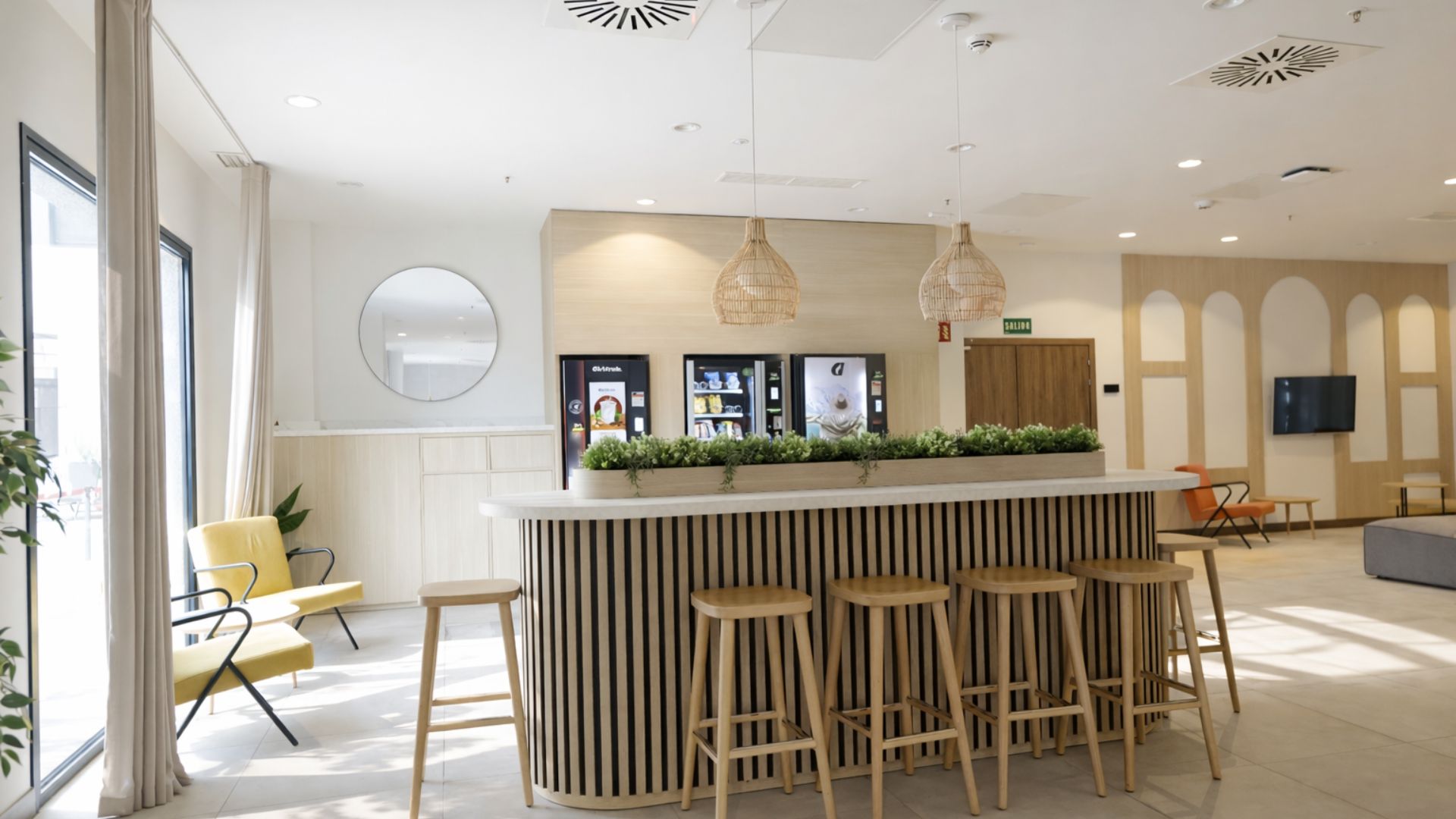 Zona de cafetería y cocina compartida en residencia de estudiantes en Málaga con barra alta y taburetes.