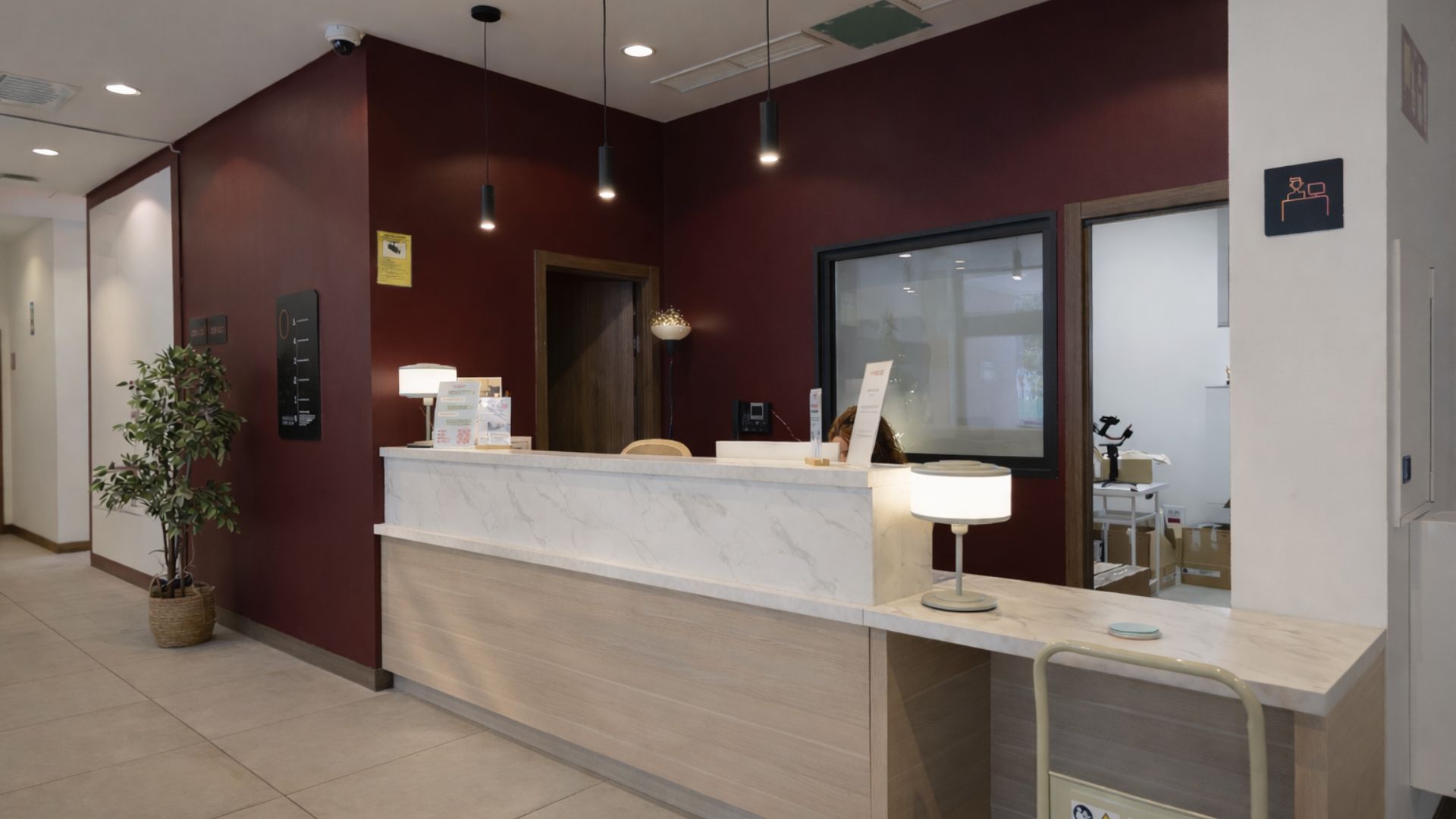 Recepción de residencia universitaria en Málaga con mostrador de atención y diseño interior contemporáneo.