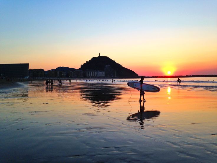 Estudiantes en la playa de Zurriola al atardecer con tablas de surf